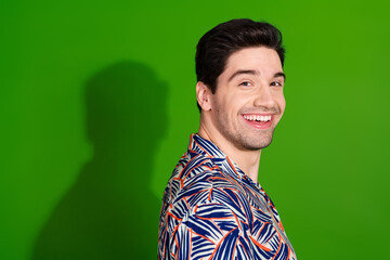 Canvas Print - Side profile photo of optimistic pleasant guy with stylish haircut dressed print shirt toothy smiling isolated on green color background