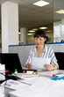 © Jovo Jovanovic/Stocksy - Smiling female entrepreneur working at desk in office