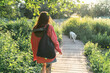 © Basil Pind/Stocksy - Woman Walking Dog on Nature Path at Sunset