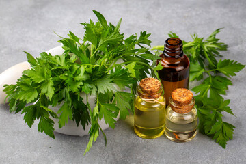 Wall Mural - Parsley essential oil in a glass bottle on old wooden table. Petroselinum crispum extract. Healthy food,herbal medicine or naturopathy concept.