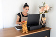 © Alvaro Lavin/Stocksy - Pet groomer working on laptop at reception desk with dog figurine