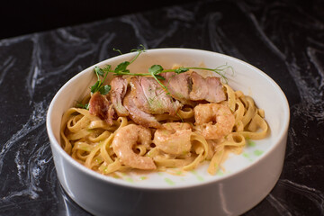 Enjoy a bowl of tasty pasta with shrimp and crispy bacon, garnished with fresh herbs