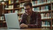 © Damerfie - Young Man Working on Laptop in Library