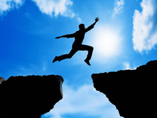 silhouette of a man leaping across a gap between two cliffs against a bright blue sky with scattered