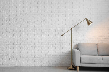 Wall Mural - Glowing lamp with sofa near white brick wall in room