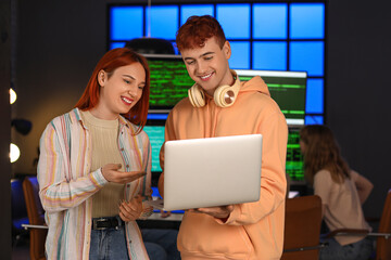 Canvas Print - Young programmers working with laptop in office at night