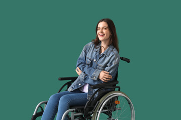 Wall Mural - Young woman in wheelchair on green background