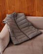© Elena Kharichkina/Stocksy - Gray Puffer Vest on Couch