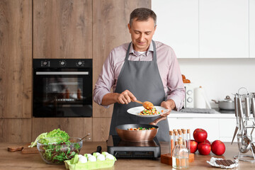 Mature man with fried vegetables in kitchen