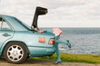 © Ulas&Merve/Stocksy - Woman Searching in Car Trunk by the Ocean