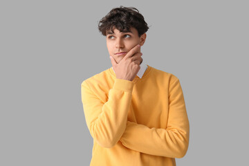 Sticker - Portrait of pondering young man on grey background