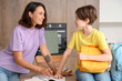 © Pixel-Shot - Mother helping her little son with homework in kitchen at home