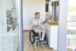 © Seventyfour - Person eating breakfast while sitting in wheelchair in modern kitchen setting with wooden floor. Holding beverage in stylish and accessible kitchen environment