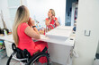 © Santi Nuñez/Stocksy - Person in wheelchair applying makeup at bathroom vanity