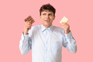 Canvas Print - Handsome young man with sweet chocolate bars on pink background