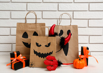 Sticker - Paper shopping bags, gifts and decorations for Halloween on table against light brick wall