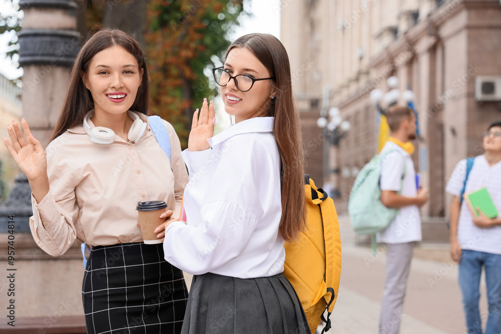 Female students waving hands near university