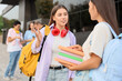 © Pixel-Shot - Female student talking to her classmate near university