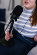 © Oleksii Syrotkin/Stocksy - Cropped photo of anonymous woman with microphone recording podcast
