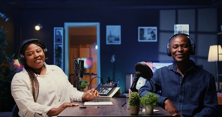 Wall Mural - Man laughing during comedy focused podcast, entertained by funny presenter. African american guest amused by talking show host telling jokes to her and audience watching at home