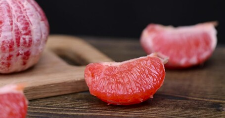 Wall Mural - Ripe red grapefruit on a black table, peeled juicy red grapefruit