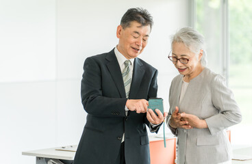 Canvas Print - オフィス・会議室にいるシニア世代のビジネスマン男女（スマホ・アプリ・検索）
