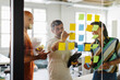 © BONNINSTUDIO/Stocksy - Colleagues using sticky notes at office