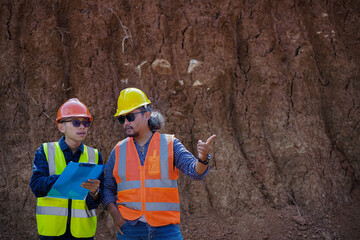 Two young male construction workers are surveying using blueprints in the field