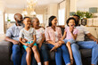 © WavebreakMediaMicro - Smiling multi-generational family sitting on couch, enjoying time together at home