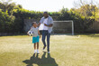 © wavebreak3 - Playing soccer, Grandfather and grandson walking on field with ball, bonding outdoors, copy space
