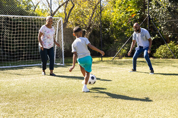 Playing soccer outdoors, grandparents and grandson enjoying time together on sunny day