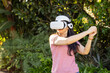© WavebreakMediaMicro - Using VR headset, woman playing virtual reality game outdoors in garden