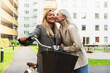 © Diego Martin/Stocksy - LGBT Woman Couple Sharing a Kiss with Bike in Neighborhood