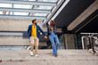 © David Prado/Stocksy - Stylish couple walking hand in hand down city stairs