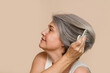 © mahalo studio/Stocksy - senior woman combing her gray hair