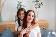 © mahalo studio/Stocksy - daughter hugging mother on couch