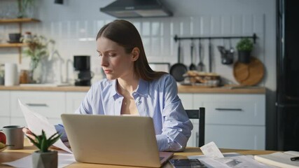 Serious woman working laptop in home office. Financial manager typing computer