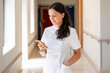 © Santi Nuñez/Stocksy - Nurse checking phone in hospital corridor
