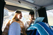 © Pedro Merino/Stocksy - Friends using tablet in bed in camper van caravan
