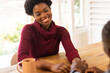© Wavebreak Media - Smiling African American woman in red sweater holding hands with partner at wooden table