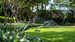 © Sinechana - 07240954 244. An automatic sprinkler system irrigating a perfectly manicured green lawn, with water jets arching through the air and a backdrop of a beautifully landscaped garden, highlighting the