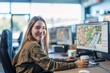© Larisa - Smiling woman working with dual monitors displaying maps