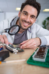 happy bearded man repairing motherboard from pc