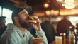 © forenna - detailed view of a man taking a big bite of a burger in a bar, the look of satisfaction on his face capturing the relief of a long day ending. photo