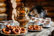 © Artemiy - A Russian samovar with cups of hot tea and pretzels on a rustic table.