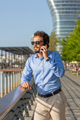 Wall Mural - Young businessman using smartphone by the riverside