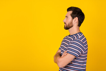 Side photo of handsome confident model new haircut in striped t shirt crossed hands looking barbershop isolated on yellow color background