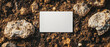 © pawimon - A blank photo frame is placed on soil surrounded by rocks, creating natural and earthy setting. This mockup is perfect for showcasing designs or artwork.