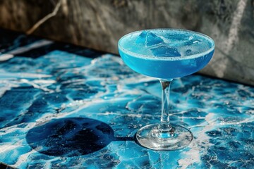 Poster - Blue cocktail standing on a bar countertop with ice cubes on a sunny day