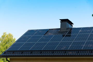 solar panels on home roof against blue sky and trees. green energy concept.